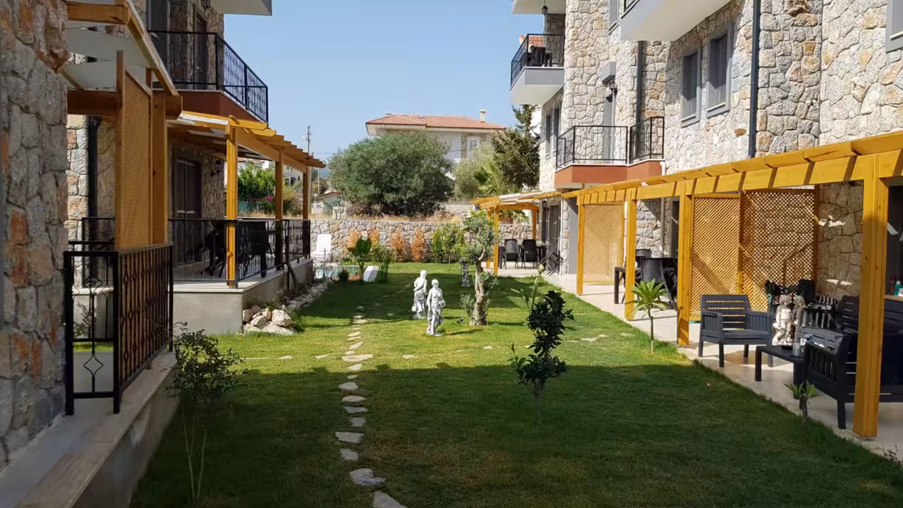 Villa Nora’nın doğal taş yapıları arasındaki bakımlı yeşil bahçe