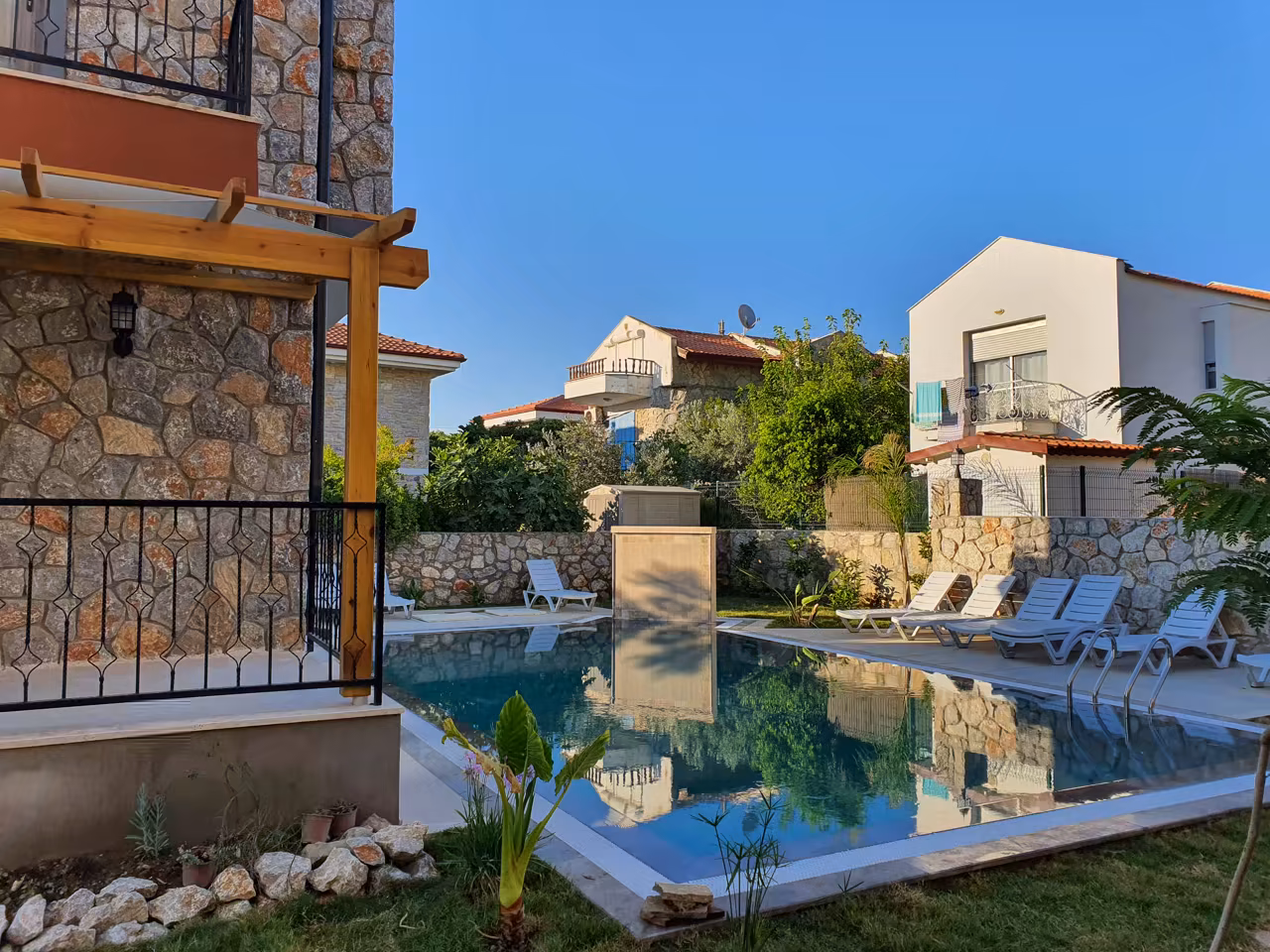 Villa Nora yüzme havuzu, doğal taş yapı ve çevresindeki yeşil bahçe